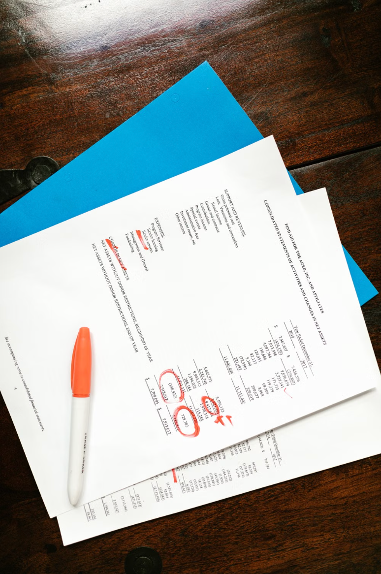Financial statement pages marked up in red pen during an audit review